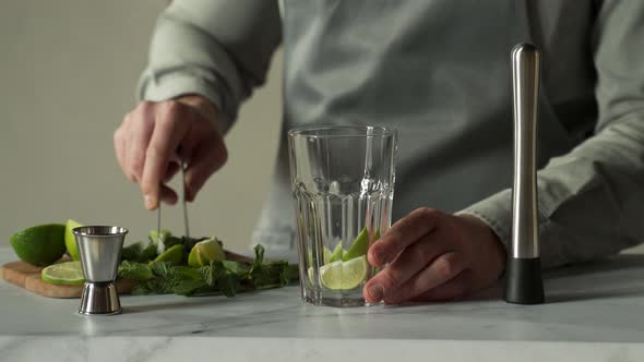Bartender Prepares a Cocktail Mojito Using the Madler alt