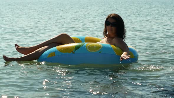 Summer vacation A woman in a bikini on an inflatable mattress with lemons swims in the sea.