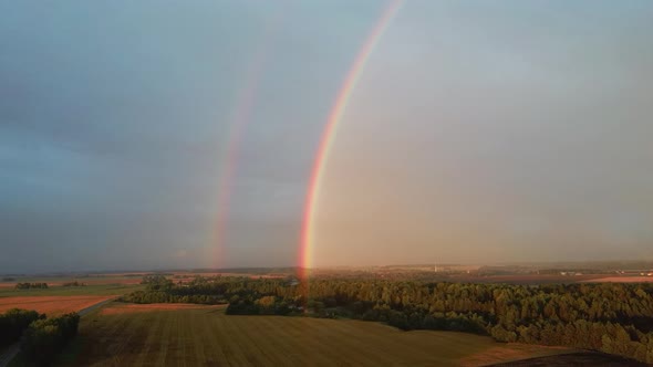 Dark Thunderstorm Clouds and Double Rainbow Over Forest and Wheat Field, Areal Dron Shoot. alt