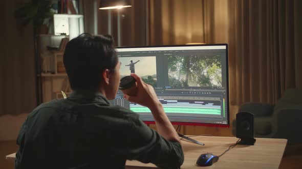 Asian Male Video Editor Works And Drinking Coffee With His Personal Computer alt