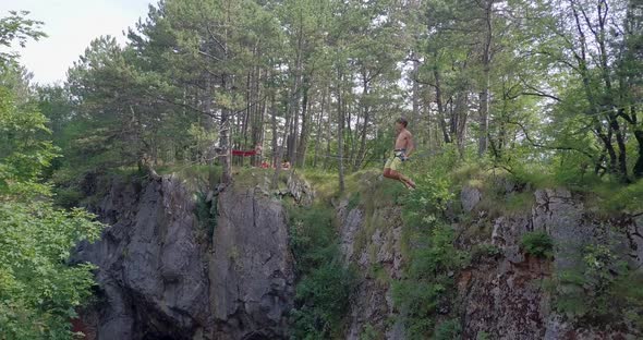 A man swinging while slacklining on a tightrope in the mountains alt