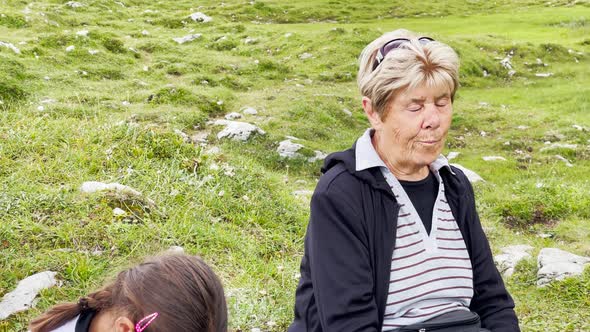 Family Relaxing and Eating Lunch After a Mountain Trail Excursion alt