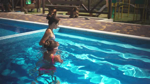 Elder Sister in Leopard Swimsuit Pulls Little Sister Out of the Pool with Blue Water alt