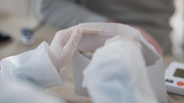 Closeup of Female Hands in Medical Gloves Counting Money in Envelope alt