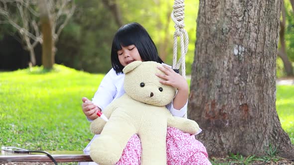 A young Asian woman playing as a teddy bear doctor.