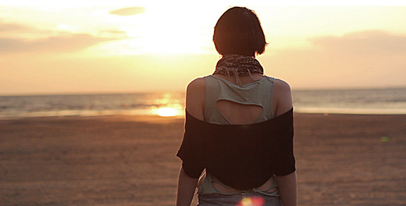 Girl is Walking on the Beach at Sunset