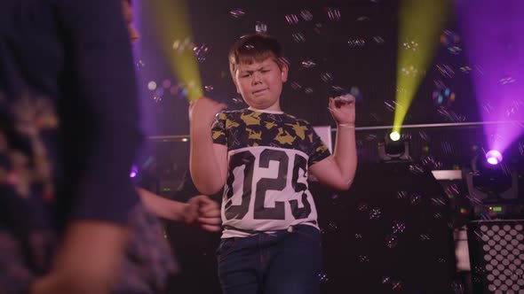 Kids Playing and Dancing with Bubbles Floating Around Them alt