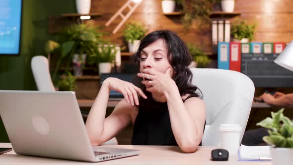 Tired Businesswoman Yawns While Working on the Laptop alt