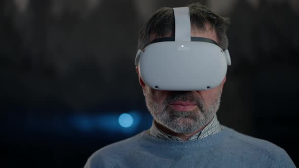 Closeup Man in VR Headset Looking Around Standing in Snow Cave with Stalactites at Background alt
