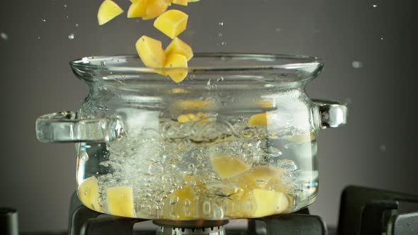 Super Slow Motion Shot of Sliced Potatoes Falling Into Boiling Water  alt