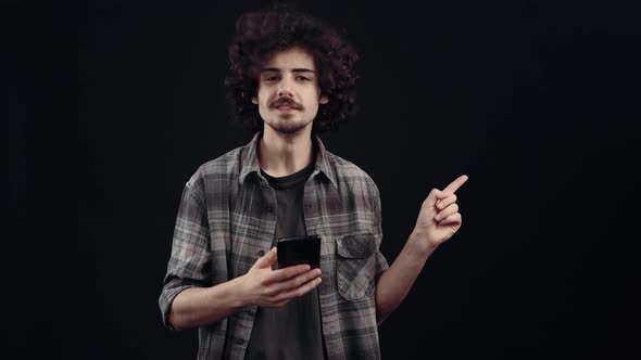 The Focused Young Man Looks at the Phone and Then Points with His Index Finger Asking If This is alt