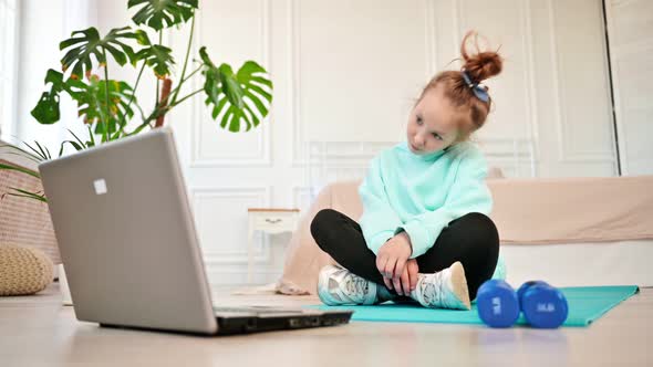 Pensive Teen Girl Sitting in Front of Laptop Doing Sports Exercises alt