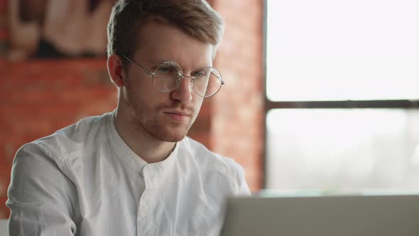 Handsome Serious Man is Typing Text on Laptop Working Remotely in Cafe Closeup Portrait of Face with alt