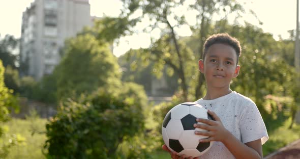 Cute Black Boy Holding a Soccer Ball at Playground alt
