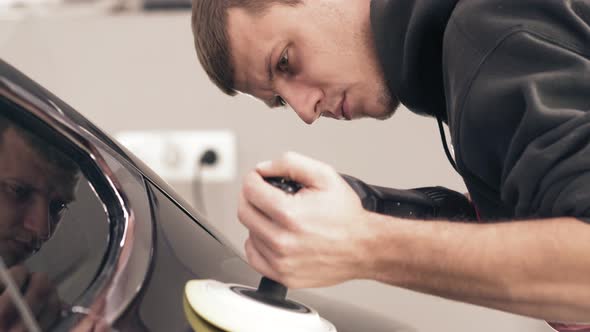 Closeup Footage of Young Male Worker Taking Care of Black New Car Polishing It to Achieve Glancy alt