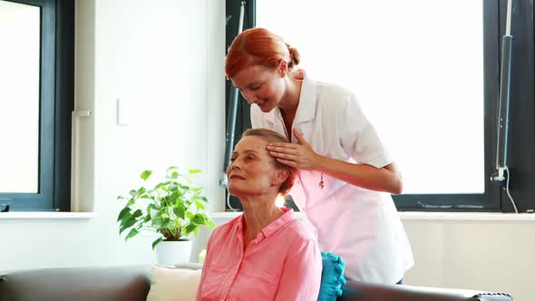 Nurse doing facial massage to her senior patient alt