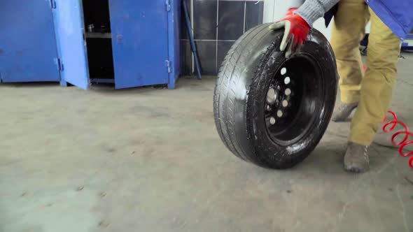 Worker rolls a wheel in a car repair shop