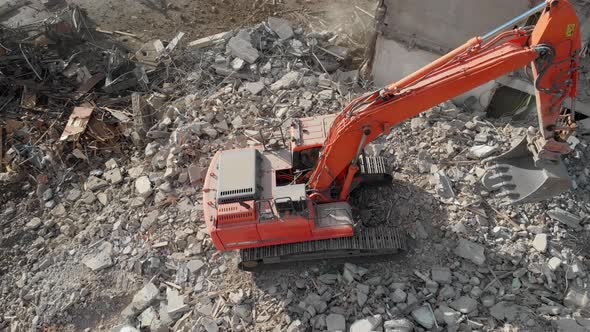 An Excavator Tractor Digs the Concrete Ruins of a Collapsed House with a Bucket