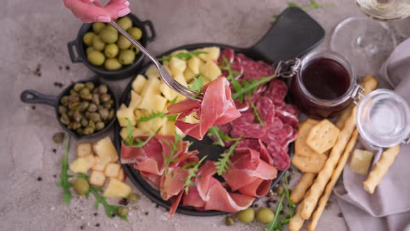 Meat and Cheese Plater at Domestic Kitchen  Woman Pricks Piece of Prosciutto Ham on a Fork alt