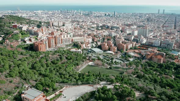 Aerial view; panorama of Barcelona city, green parks and orange rooftops, sea in the background