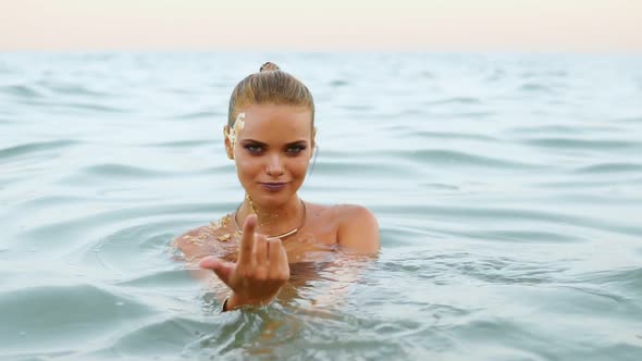 Sexy Attractive Woman in the Water on the Beach Beckons to Follow Her and Looking in the Camera and alt