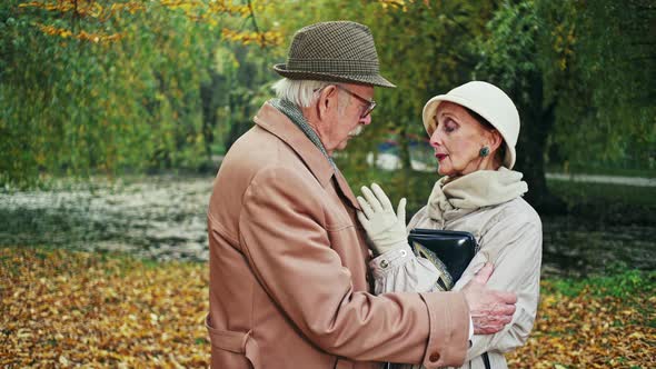 Elderly Man Consoling Sad Woman in Autumn Park alt