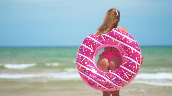Buttocks Girls Dancing with Pink Donut. Girl in Pink Bicini on the Beach. Beautiful Sexy Woman alt
