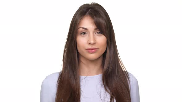Young Caucasian Brunette Woman Smiling and Making Face Over White Background alt