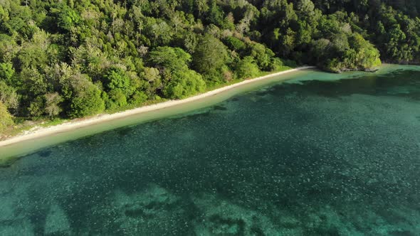 Aerial: flying over tropical Hatta island white sand beach Banda Islands Maluku alt