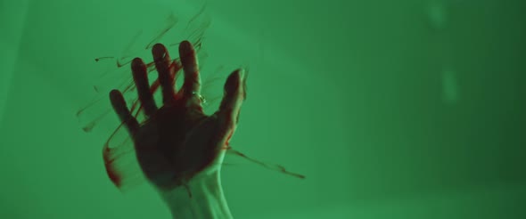 Bloody hand scratching glass, trapped person trying to escape, horror movie shot alt
