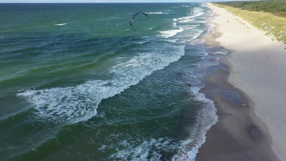 AERIAL: Rotating Shot of Stranded Surfer Waiting for a Wave on a Beach on a Sunny Day alt