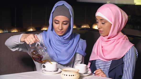 Two Young Beautiful Muslim Business Women in Hijab Drinking Tea in Cafe