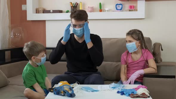 The Older Brother Shows the Children Protective Glasses and a Respirator . Social Distancing and
