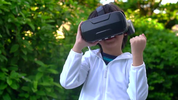 Asian Child With Virtual Reality Headset Touching Outdoors alt
