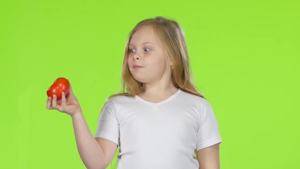 Little Girl Looks at a Tomato, Admires It and Shows a Thumbs Up. Green Screen alt