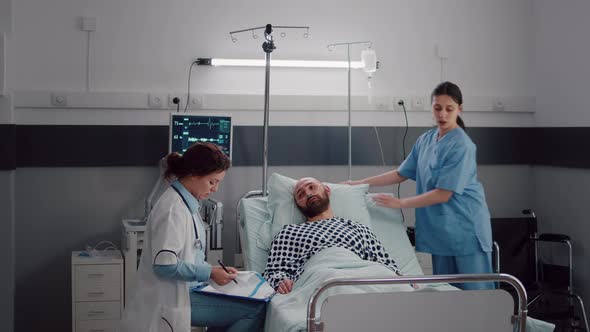 Practitioner Doctor Monitoring Sick Man Writing Disease Treatment on Clipboard alt