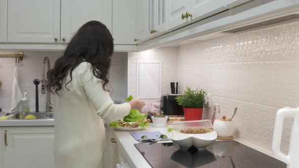 Woman Cooking Festive Dinner in the Kitchen Making Toast with Cucumber and Caviar alt