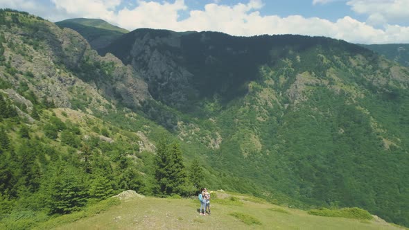 Lovely Couple Taking Selfie Photos at the Mountain Top with Deep Valley Below alt