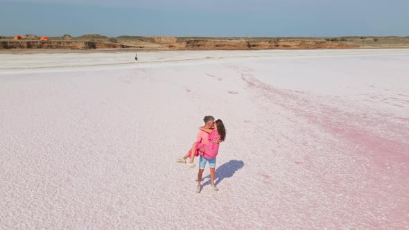 Circle Drone Flight and Aerial View of Happy Romantic Lovely Couple in Pink Wear Standing on White alt