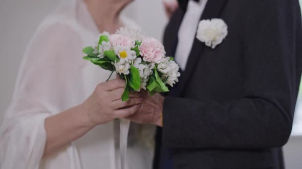 Closeup Bridal Bouquet in Senior Hand with Happy Groom and Bride Dancing in Slow Motion alt