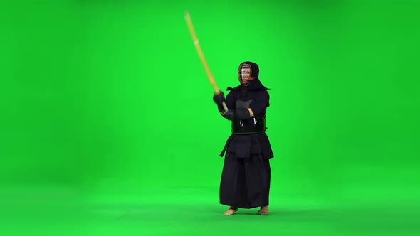 Masculine Kendo Warrior Practicing Martial Art with the Bamboo Bokken on Green Screen. alt