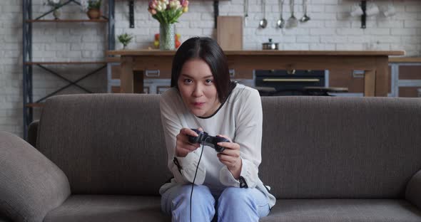 Energetic Young Asian Woman Using Jostick Wireless Gamepad Controllr Playing Modern Video Games on alt