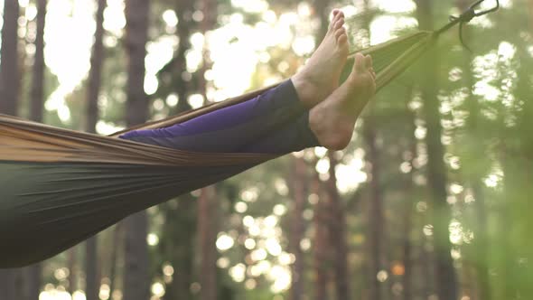 A Happy Girl is Resting in a Summer Forest on a Green Hammock alt