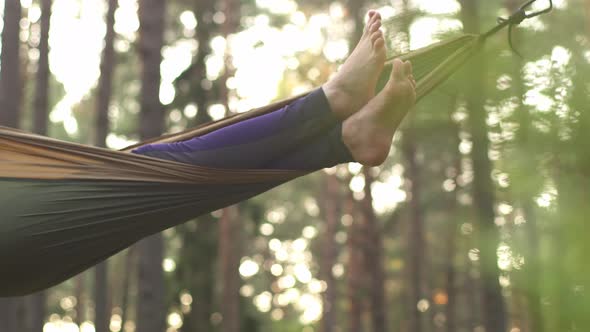 A Happy Girl is Resting in a Summer Forest on a Green Hammock