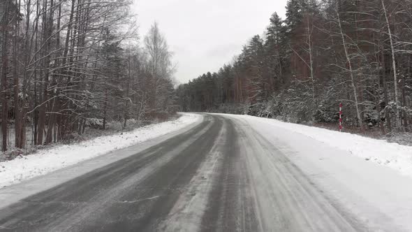 Car Rushes Along a Snow-covered Road in the Woods. Dangerous Driving in Icy Conditions alt