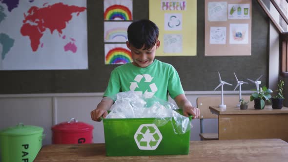 Boy holding a recycle container in the class at school alt