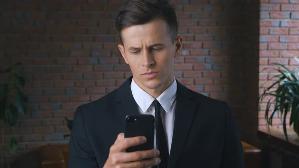 Male Professional Holding Smartphone Texting Message Standing at Modern Office