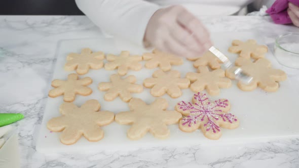 Step by step. Icing snowflake shaped sugar cookies with pink royal icing. alt