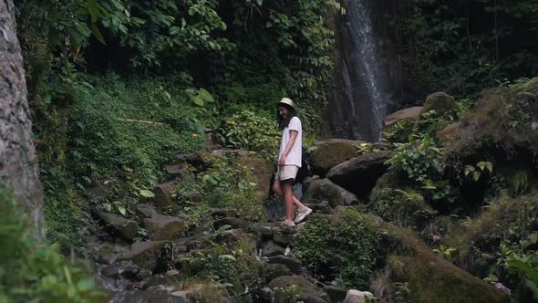 Girl Walks in Jungle at the Waterfall