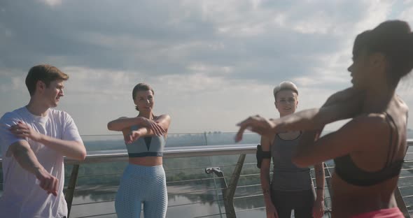 Young Athletes Do Arm Stretching After Latin Lady on Bridge alt